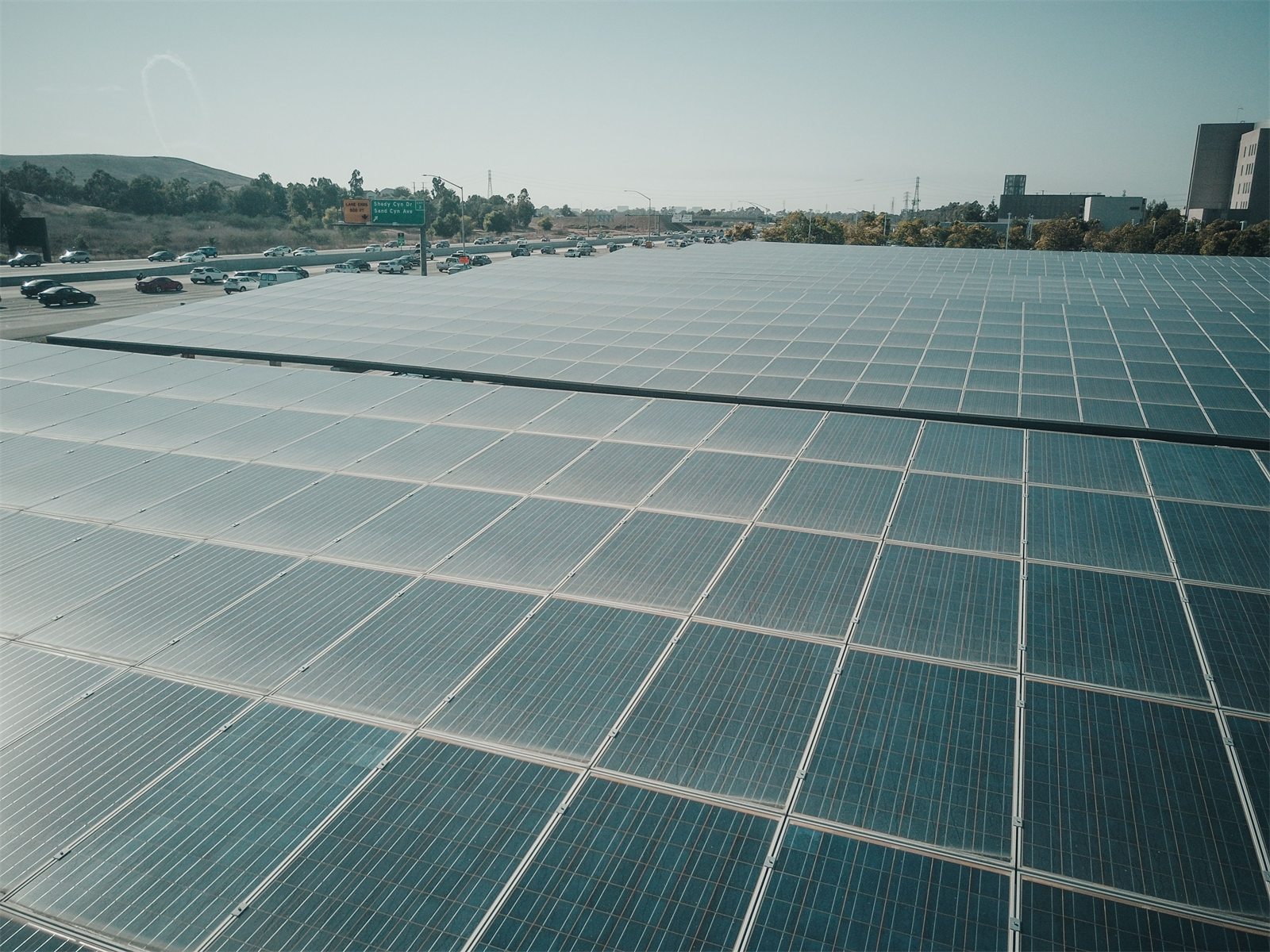 A large solar array stretching toward a highway